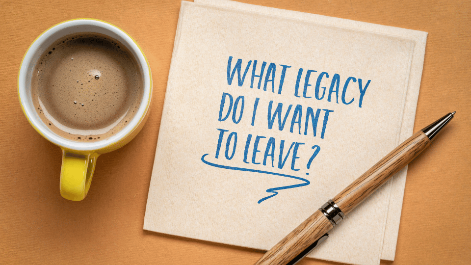 Yellow tabletop as a background with a coffee cup and pen on a note reading, "What Legacy Do I Want to Leave?"