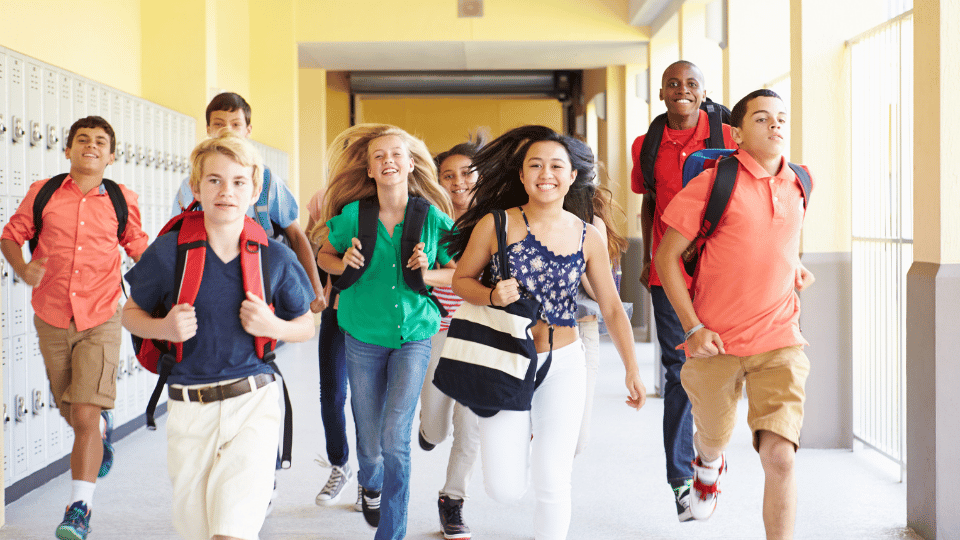 Teen students running down the hallway towards the camera.