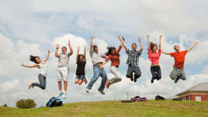 Teenage kids jumping in the air on top of a hill.