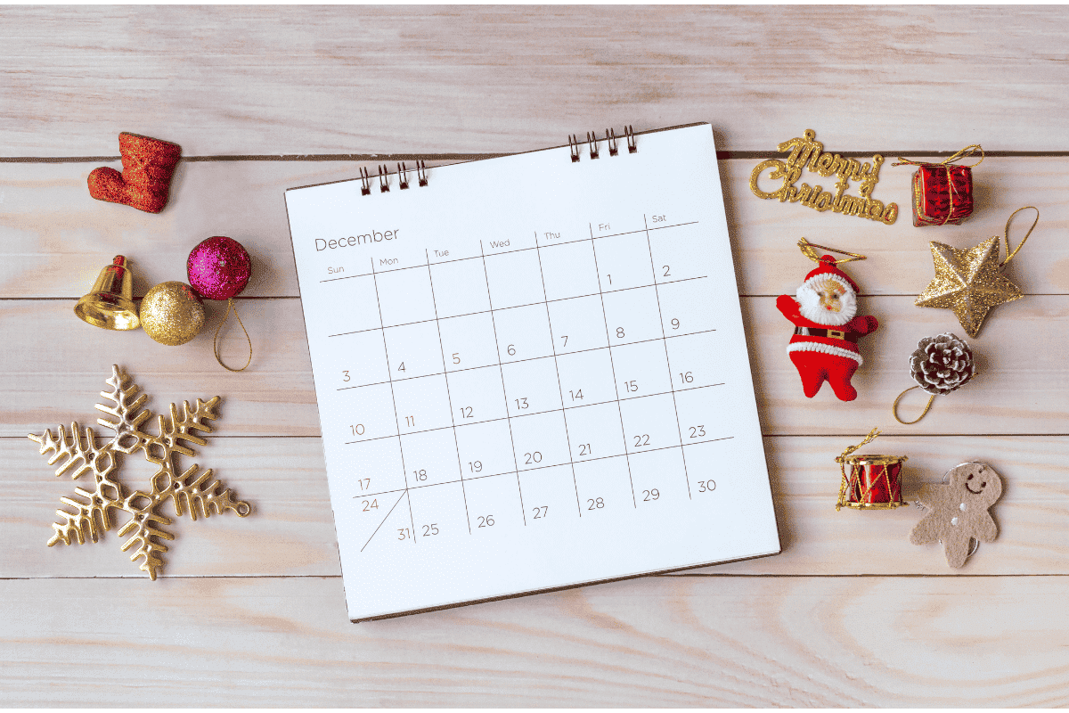 A December calendar on a wooden table surrounded by Christmas ornaments, representing the busy and often stressful holiday season for families and teens.