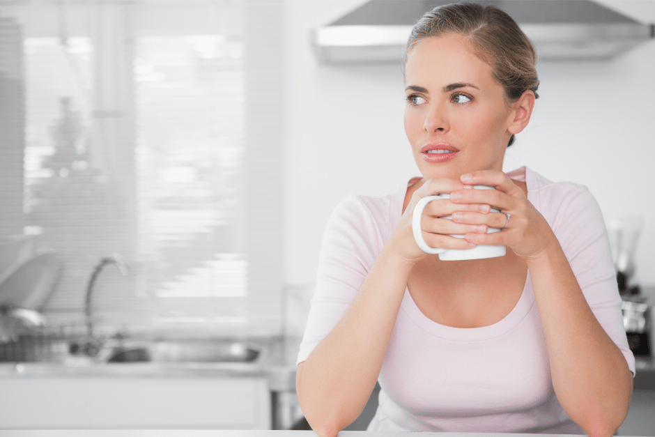 Mother sitting pensively with coffee mug in hands in a kitchen