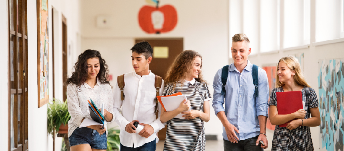 Group of high school kids walking down a school hallway.