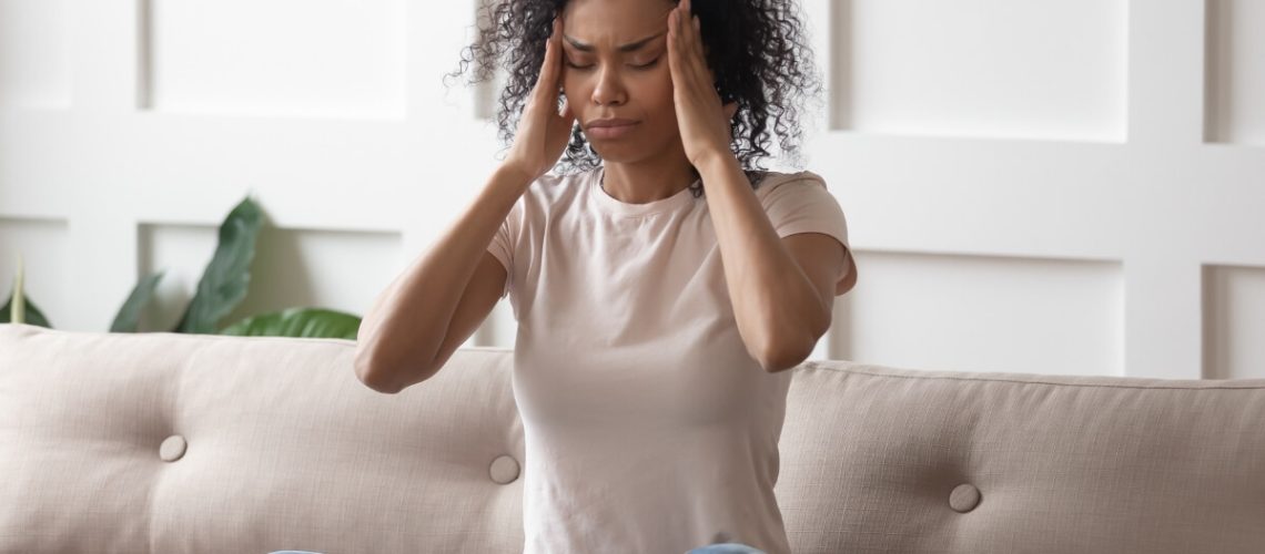 A Black woman massaging her temples as though she is stressed or anxious.